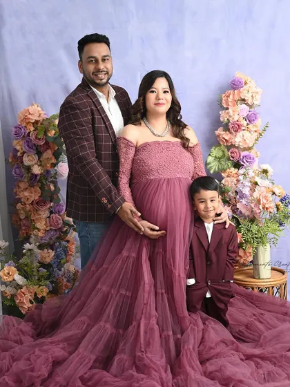 A picture-perfect family portrait. The coordinating mauve and burgundy outfits and the pastel floral background create a rich and harmonious image.