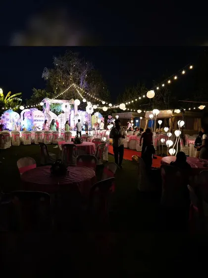 An outdoor setup for a first birthday party with a butterfly theme. The space is decorated with string lights, paper lanterns, and themed elements to create a magical "Enchanted Garden" for the little one's celebration.