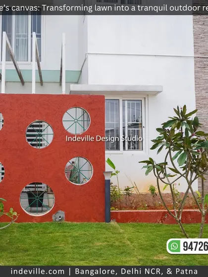 A striking red accent wall with circular openings, adding a bold and modern architectural element to this backyard design.