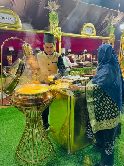 A guest being served at my Mughlai food station, which features ornate golden chafing dishes.