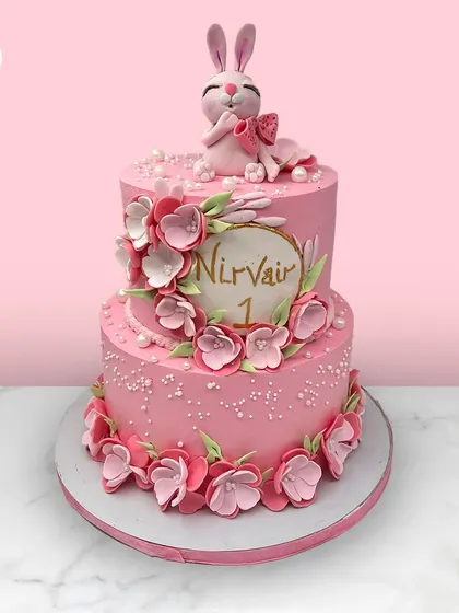 A lovely two-tiered pink cake for Nirvair's first birthday, decorated with a cascade of pink flowers and topped with a cute bunny.