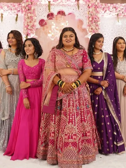 The bride and her bridesmaids pose for a fun group photo, showcasing a rainbow of colorful lehengas and happy smiles.