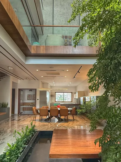 Another view of the open-plan living and dining area, showing the connection to the upper floor and the central role of the indoor water body and greenery.