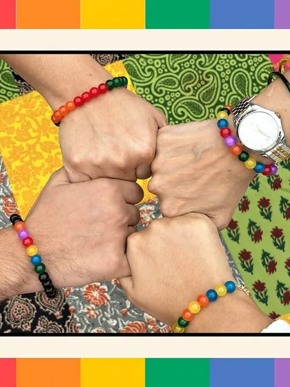 A group of colleagues showing their solidarity with a fist bump, each wearing the Ally Bracelets they made during our Pride workshop. It's a visual representation of a supportive and inclusive team.