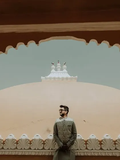 A majestic portrait of the groom. Posed against the backdrop of the palace domes, this shot is framed by a traditional archway, creating a regal and powerful image.