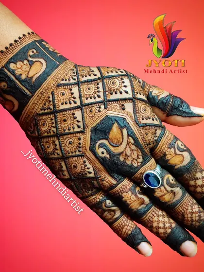 A stunning back-of-hand design for Karva Chauth, featuring multiple peacock motifs and intricate checkerboard patterns.