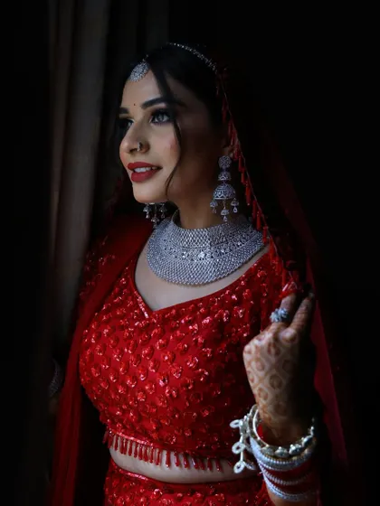 A dramatic, low-light portrait of the bride. The makeup is strong enough to stand out even in shadows, with a bold red lip and defined eyes making a statement.