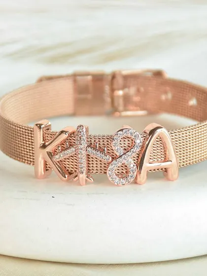 A close-up of the 'KISA' name bracelet in a beautiful rose gold finish. The sparkling ampersand charm adds a touch of glam between the initials.