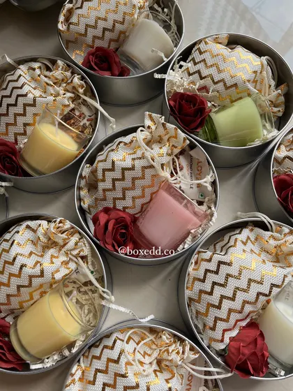 A look inside our return gift tins. This option includes a small scented candle and a potli bag filled with dry fruits or chocolates, offering a simple yet elegant thank you gift for your guests.