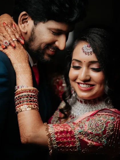 An intimate portrait showing the bride's beautiful smile and henna-adorned hands as she embraces the groom. It’s a shot filled with love and happiness.