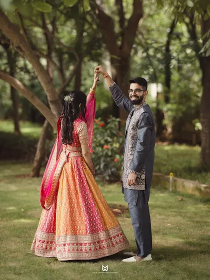 A playful moment during the Roka photoshoot. The groom twirls his bride, creating a dynamic and joyful image that showcases her lehenga.