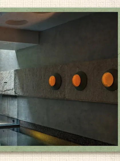 At the Kumar Residence, a stone water feature and custom wall-mounted lights create a serene and contemplative atmosphere. The design uses natural materials and the gentle sound of water to craft a peaceful sensory experience.