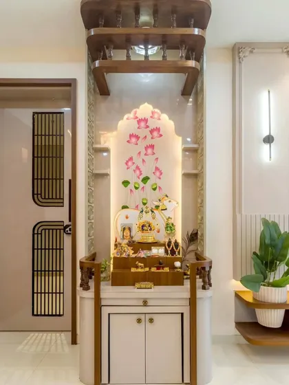 A close-up of a custom mandir with a beautiful lotus-themed backlit panel. The wooden frame and white storage cabinet create a clean and elegant look, perfect for a modern home.