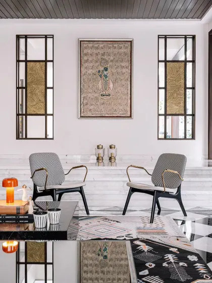 Symmetry and balance are key to creating a formal yet welcoming living space. Here, two elegant armchairs frame a central art piece, creating a perfect spot for conversation. The black and white checkered floor adds a classic, graphic touch.