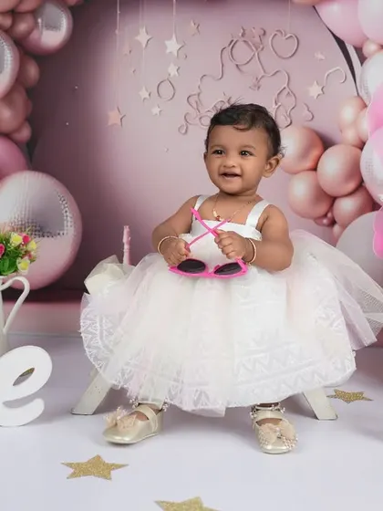 A true star in the making! Adding fun accessories like these heart-shaped sunglasses brings out the playful side of a one-year-old during her milestone photoshoot.