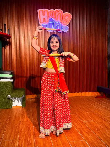 A joyful student in a traditional red and yellow Garba outfit. We encourage every child to express themselves through dance, and her happy expression says it all.