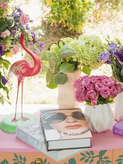 A close-up of the details, including fashion books, a pink flamingo, and lush arrangements of sunflowers, hydrangeas, and roses.