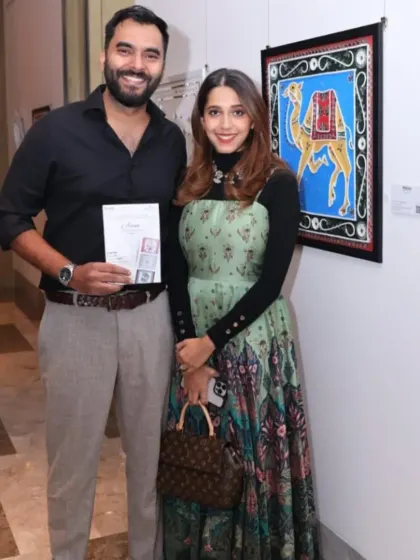 Guests at the 'Aaina' exhibition, posing with a colorful artwork of a camel.