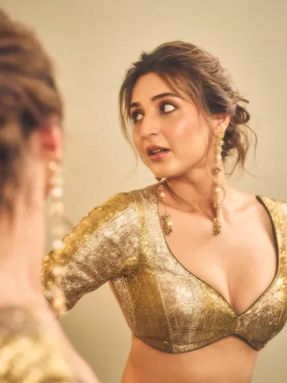 This candid mirror shot captures the final touches. It highlights the intricate sequin work on the blouse and the delicate design of the pearl-and-gold drop earrings.