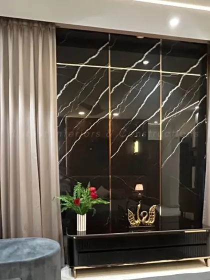 The entertainment wall in the bedroom is crafted from black marble with gold veining, creating a sleek and luxurious look. The design cleverly conceals wiring and provides a stylish backdrop for the television.
