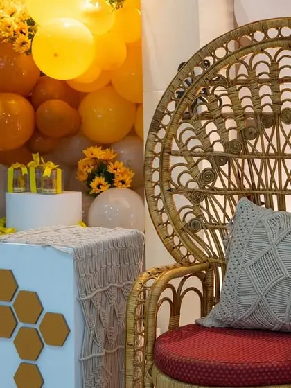 A close-up of the "Mom To Bee" setup, featuring a beautiful peacock chair for the guest of honor, surrounded by sunflowers and honeycomb decor.
