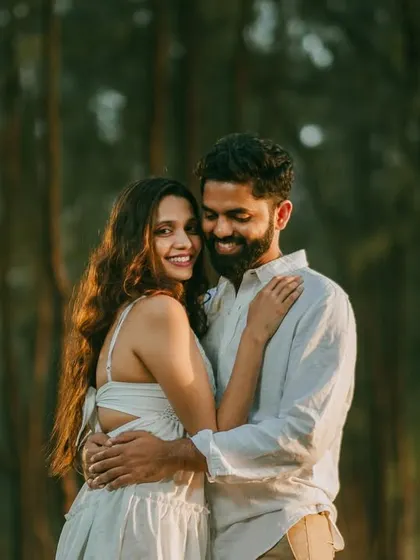 A beautiful, sun-dappled portrait of the couple in the woods. The golden light filtering through the trees creates a magical, romantic effect.