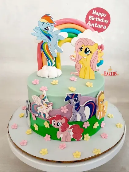 A colorful and cheerful "My Little Pony" cake for Antara's 5th birthday. This minimal-fondant cake features Rainbow Dash, Fluttershy, and the rest of the pony friends on a grassy green field with a big rainbow.