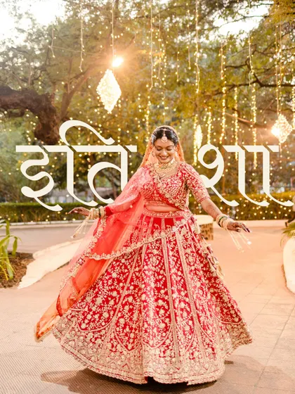 Poetry in motion. A stunning bridal portrait with the bride twirling in her red lehenga against a backdrop of fairy lights.