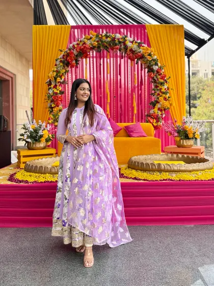 The vibrant colors of the Mehendi decor beautifully complement the soft lilac of my Anarkali suit.