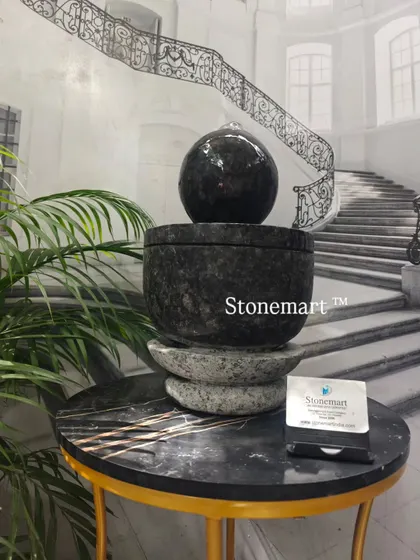 A different angle of the granite modern tabletop fountain, showing the reflection of light on the wet sphere.