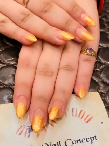 A beautiful set of almond-shaped nails with a shimmery, golden-yellow polish. The subtle ombre effect gives them a warm, sun-kissed glow.