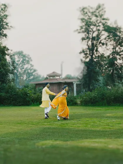 A wide shot of the couple enjoying a playful run across the lawn during their Haldi event, capturing their carefree spirit.