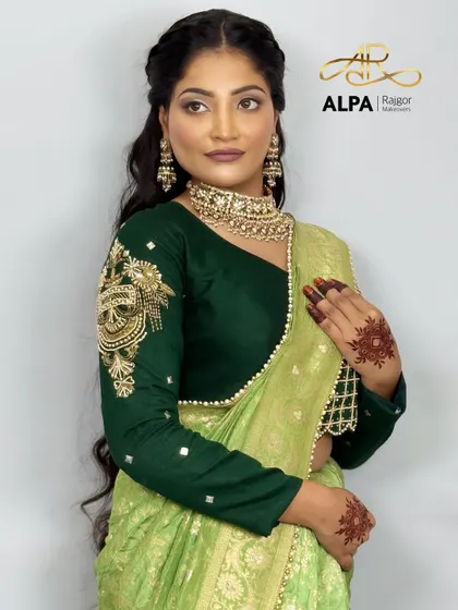 A soft and romantic hairstyle for long hair, paired with a beautiful green saree. The makeup is kept subtle and glowing.