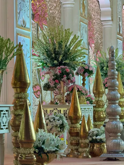 A detail shot of the traditional brass and silver decor pieces that line the stage. These elements, combined with fresh flowers, add a touch of royal grandeur.