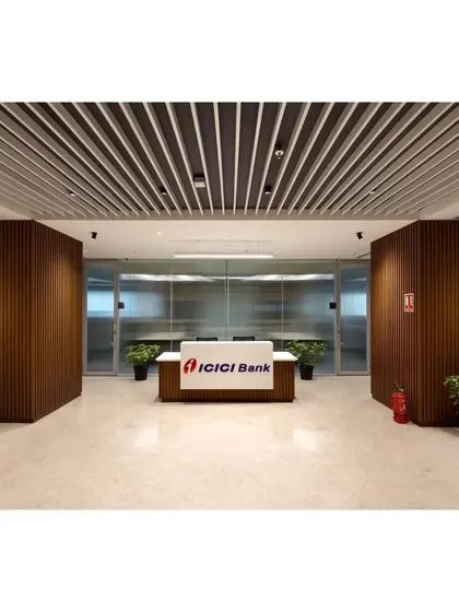The primary reception desk at the ICICI Bank corporate office. We used a clean, minimalist desk design framed by rich, vertically slatted wood paneling and a louvered ceiling to establish a sense of structure and professionalism.