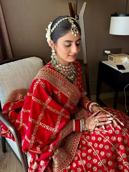 The complete bridal vision. Anmol's look features a classic hair bun with gajra, complementing the soft, traditional makeup for her wedding day.