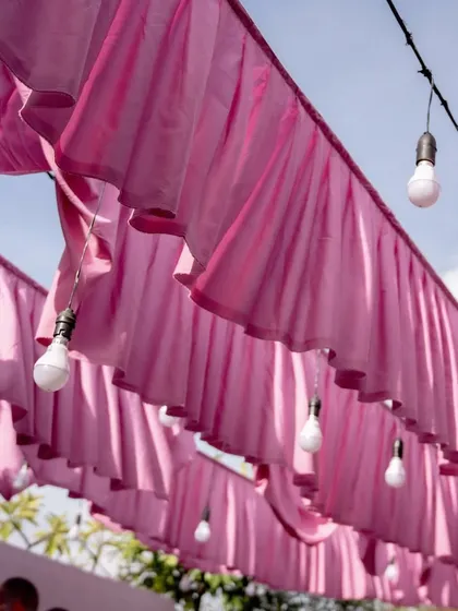 A shot of the pink fabric drapes and light bulbs creating a dreamy canopy for the at-home Mehendi ceremony.