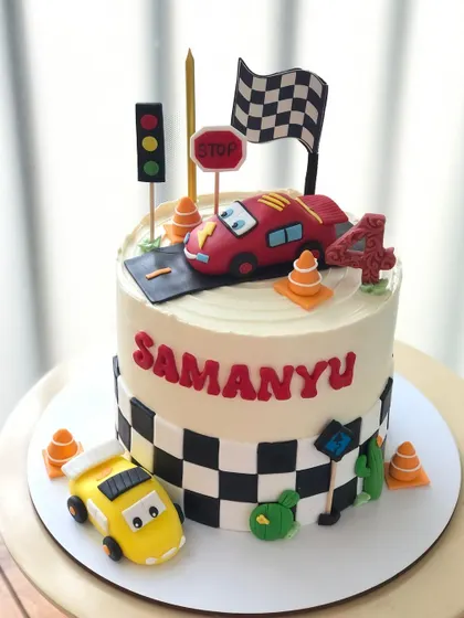 A fun race car-themed cake with checkered flags and traffic lights.