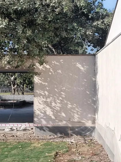 Dappled light on the exterior wall of the Alibaug house. The simple, hand-troweled finish gives the surface a subtle warmth and character.