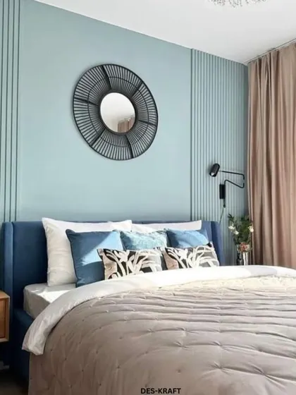 A serene bedroom with a soft blue-green accent wall, a statement mirror, and a comfortable bed, showcasing a cohesive and calming design.