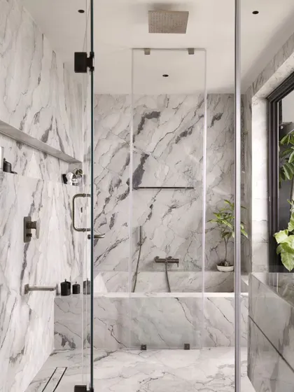 The spacious walk-in shower and bathtub, all clad in the same dramatic white and grey marble. The large window at the end opens onto a private balcony garden.