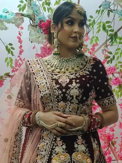 This bride chose a beautiful Kundan set with emerald green stones to contrast with her maroon velvet lehenga. The set includes a choker, large earrings, nath, and haath phool.