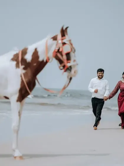 A wide-angle view of the couple and a horse on the beach, creating a sense of story and adventure for their pre-wedding session.