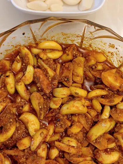 A bowl full of our Lehsun ka Achaar (Garlic Pickle). The garlic cloves are soft yet crunchy, and they are soaked in a tangy and spicy masala.