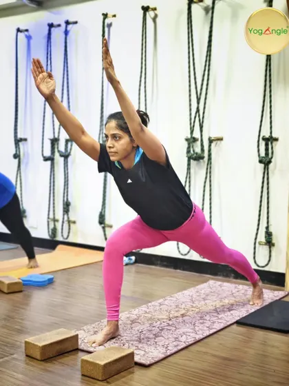 This dedicated student, who has been with us for over seven years, demonstrates a powerful Warrior 1 pose. Notice the use of blocks under her hands in a previous stage, a common technique we use to help students find the correct alignment before progressing.