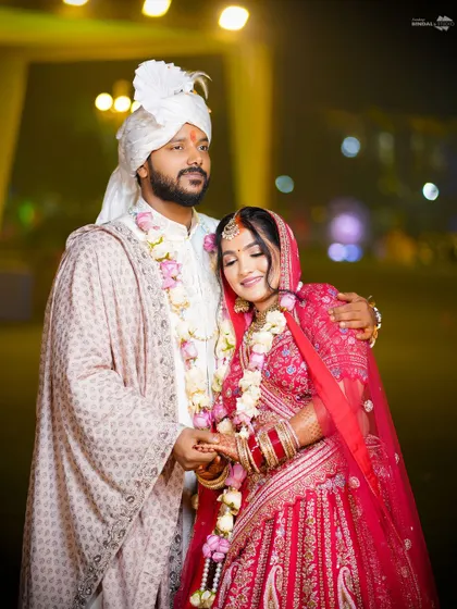 A tender moment between the couple, holding hands. The bride's red lehenga and the groom's white sherwani create a classic, romantic look.