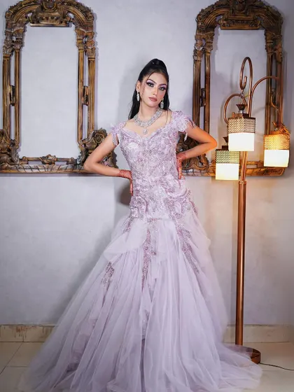 A full-length shot of our lilac gown with a tiered skirt and feathered cap sleeves.
