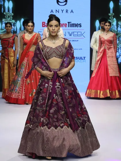 Showcased at Bangalore Times Fashion Week, this plum-colored silk lehenga is detailed with intricate floral embroidery. The look is completed with a unique organza cutwork dupatta that drapes like a cape.