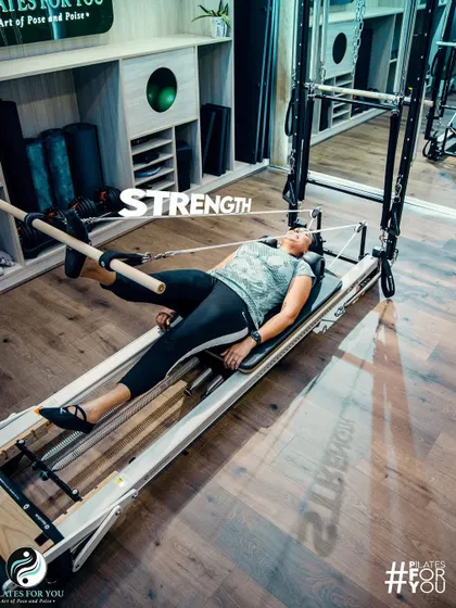 This client demonstrates how Pilates builds functional strength, using the push-through bar on the Trapeze Tower for a controlled leg press.