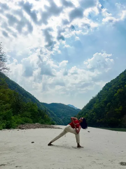 A deep stretch in Baddha Parsvakonasana, or bound side angle pose, by the river. Practicing outdoors helps deepen your connection to both your body and the earth.